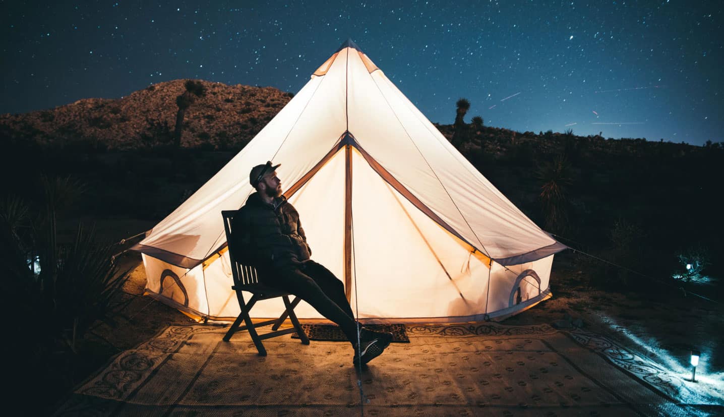 man-sitting-by-tent-with-light